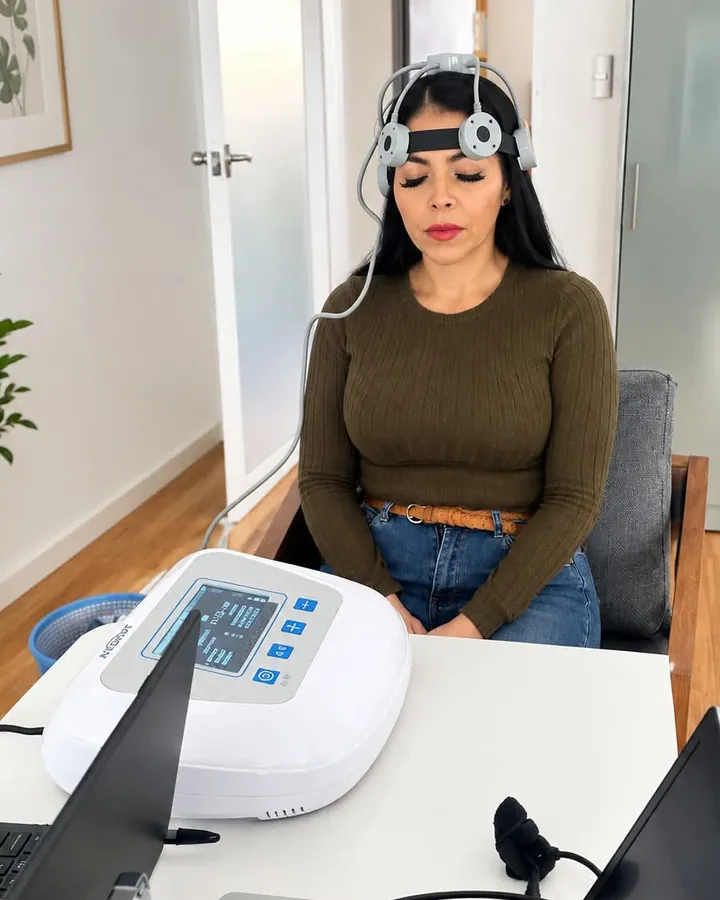 Una paciente con los ojos cerrados recibe terapia transcraneal con un equipo colocado en la cabeza.